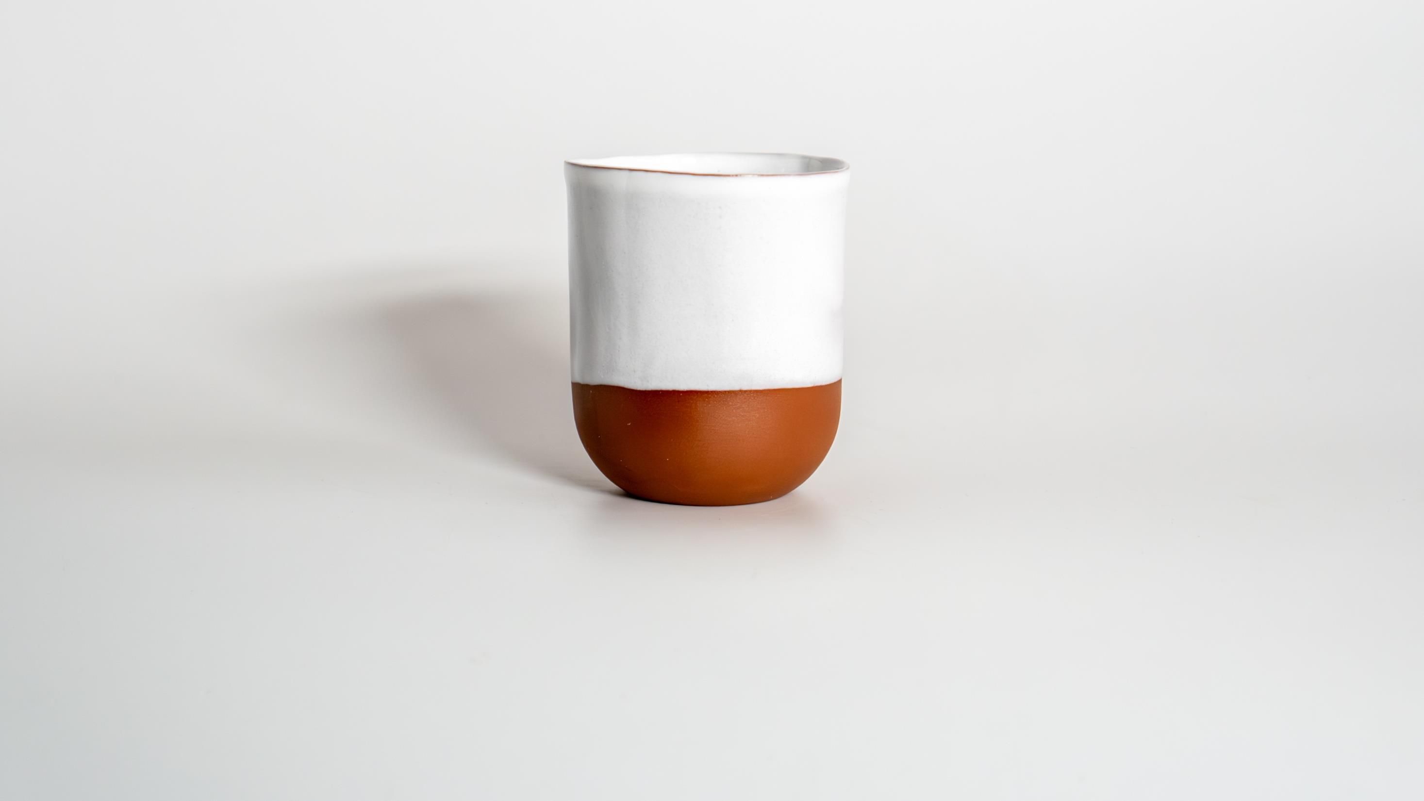 A small cup thrown from London construction clay, dipped in wood-ash glaze.